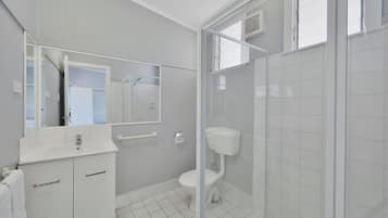 Un baño moderno con lavamanos, espejo y retrete blancos.