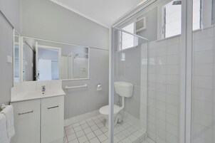 Un baño moderno con lavamanos, espejo y retrete blancos.