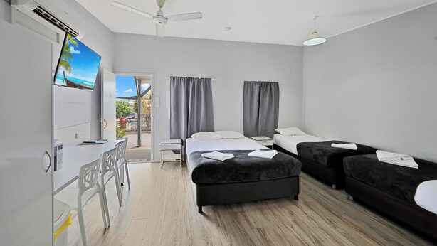 A hotel room with a bed, a desk, and a TV. There are curtains and a ceiling fan. - Ned Kelly's Motel (Tinana)