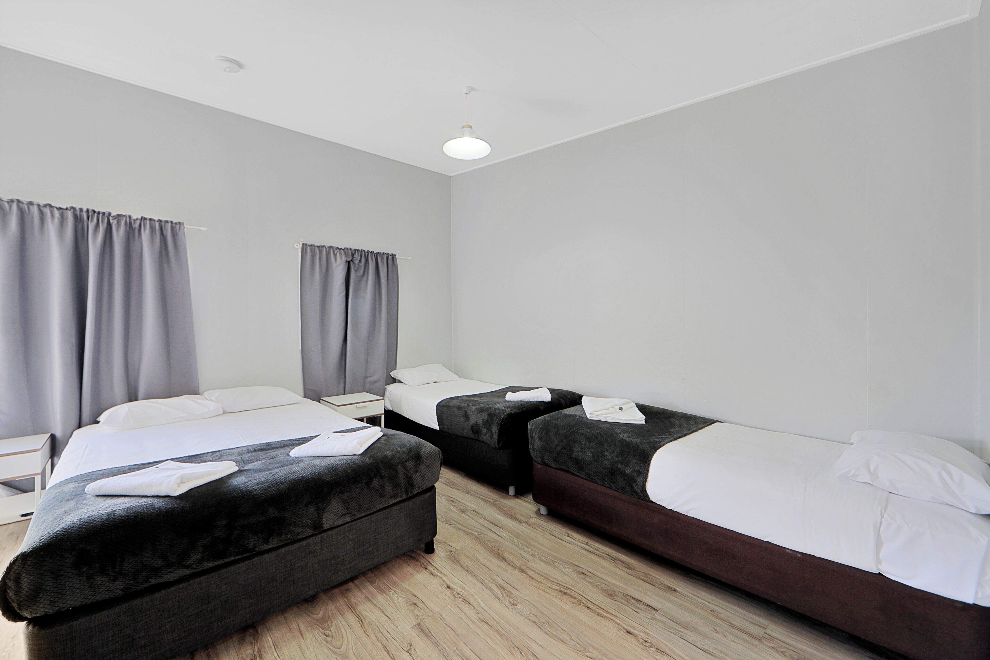 A hotel room with two beds, a nightstand, and a window with curtains.