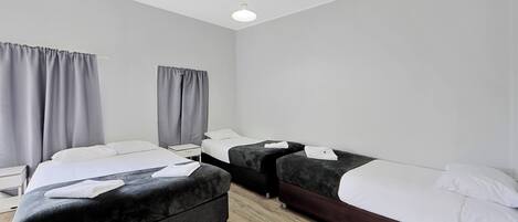 Una habitación de hotel con dos camas, una mesita de noche y un ventanal con cortinas.