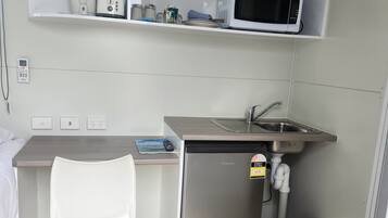 Uma cozinha compacta equipada com micro-ondas, pia e pequena geladeira.