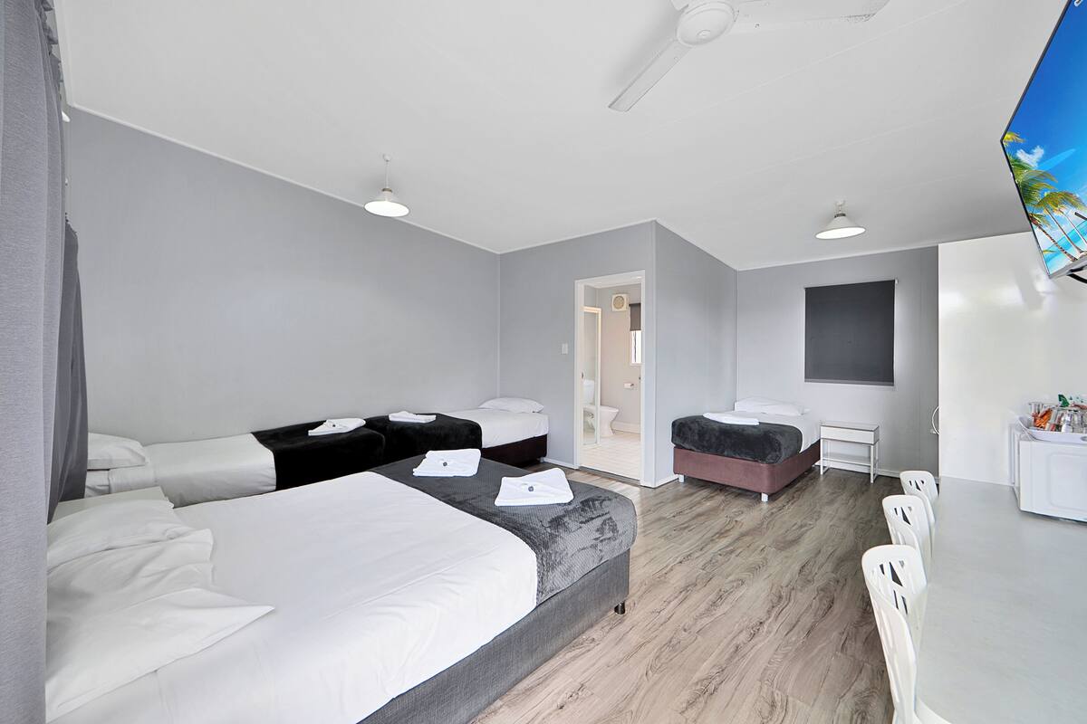 Moderni hotellihuone, jossa on suuri sänky, työpöytä ja oleskelualue.