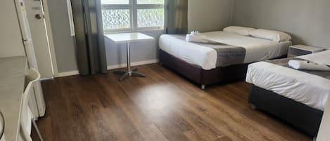 A hotel room with two beds, a small table, and a window with curtains.