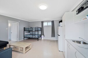 Habitación pequeña con literas, kitchenette y un rincón de descanso.