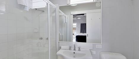 Un baño moderno con cabina de ducha de vidrio, un lavabo blanco y un espejo encima.