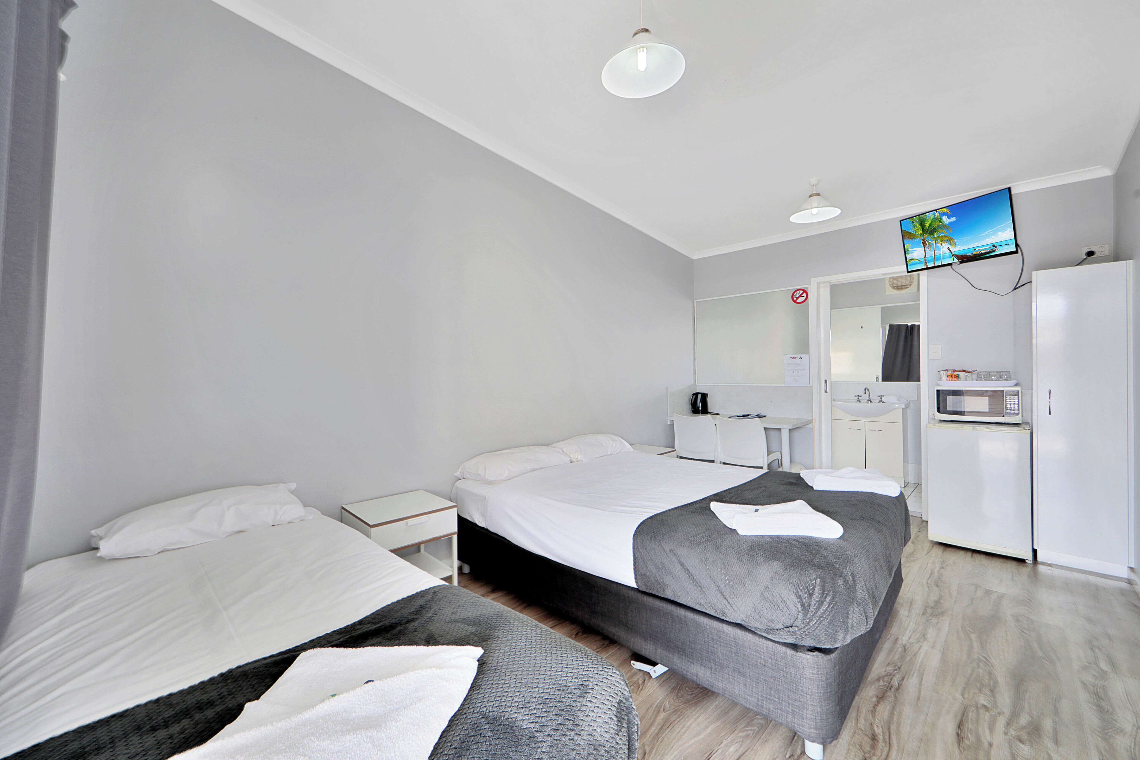 Una habitación de hotel moderna con cama, sofá, televisor, microondas y lavamanos.