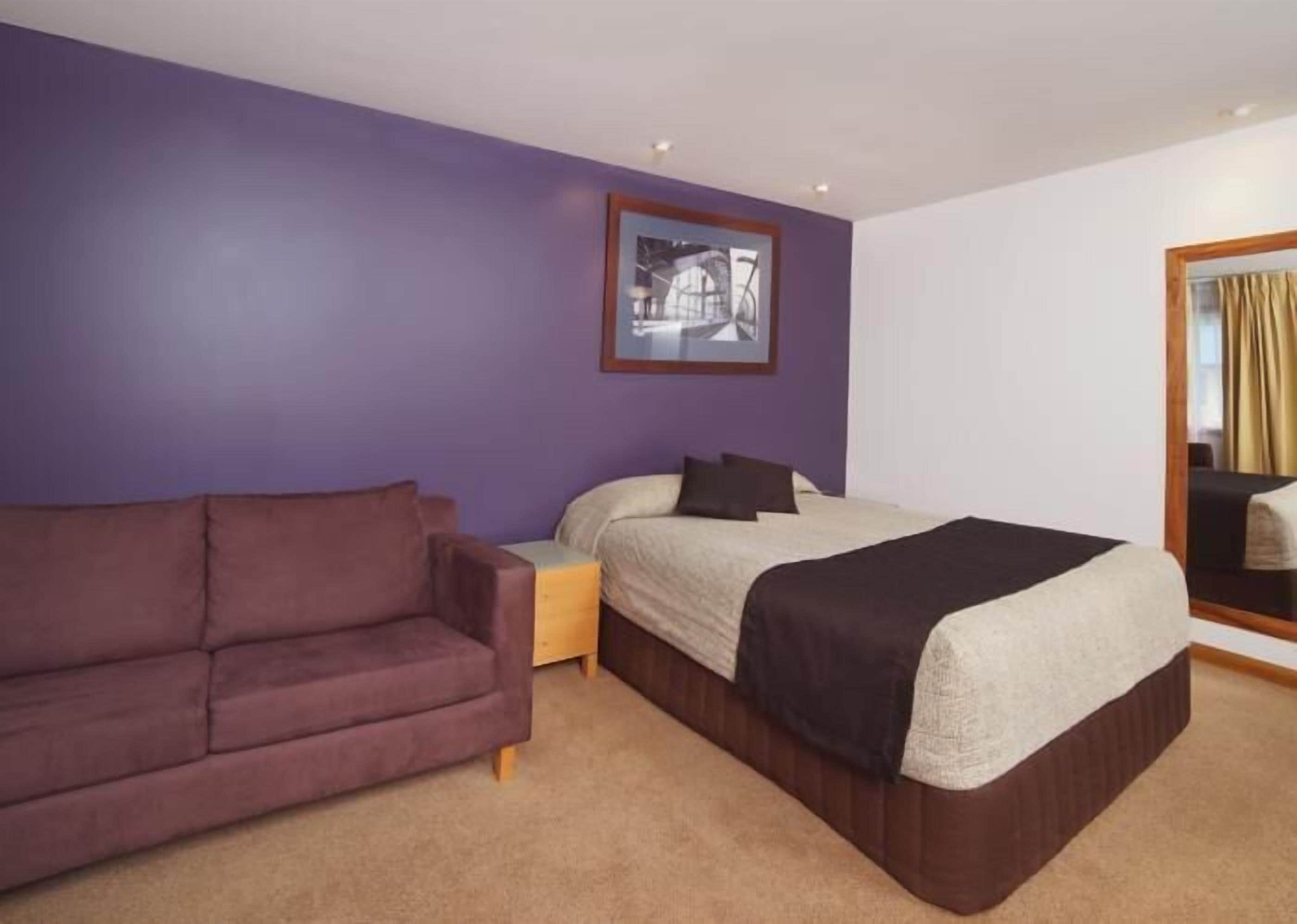 Une chambre à coucher avec un lit, un canapé et une table de chevet.