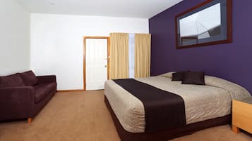 Un dormitorio con cama, sofá, puerta y ventana con cortinas.