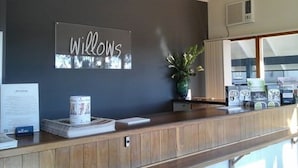 A reception desk with a sign that reads "Willows" and a potted plant. - Willows Motel Goulburn (Goulburn)