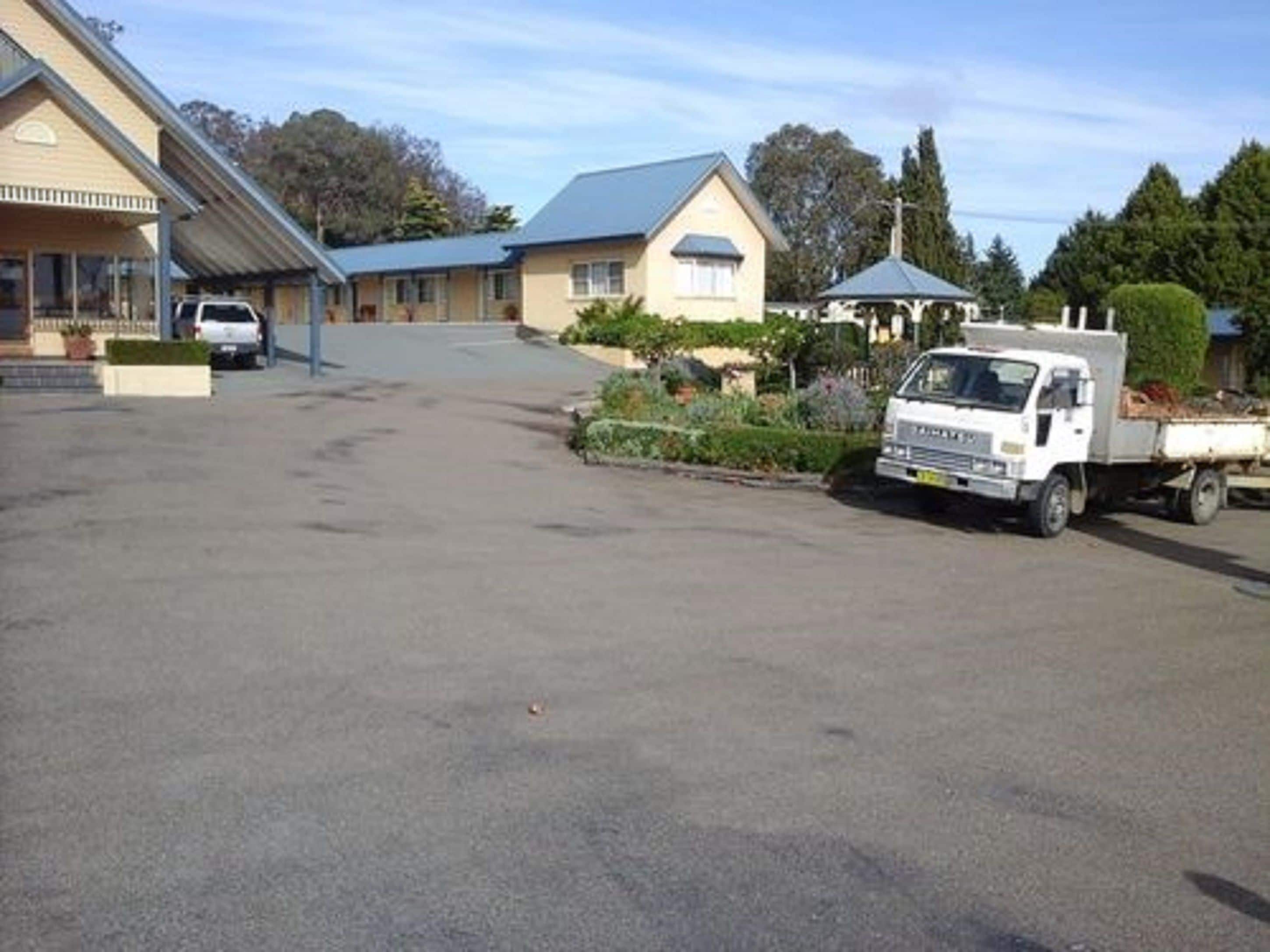 A parking area with a white truck and a building with a blue roof.