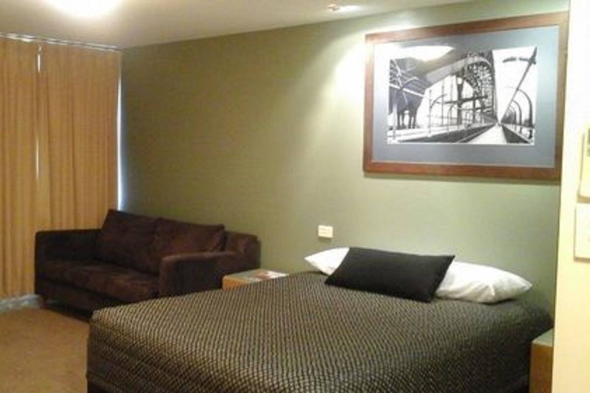 Una habitación de hotel con una cama, un sofá y un cuadro en la pared.