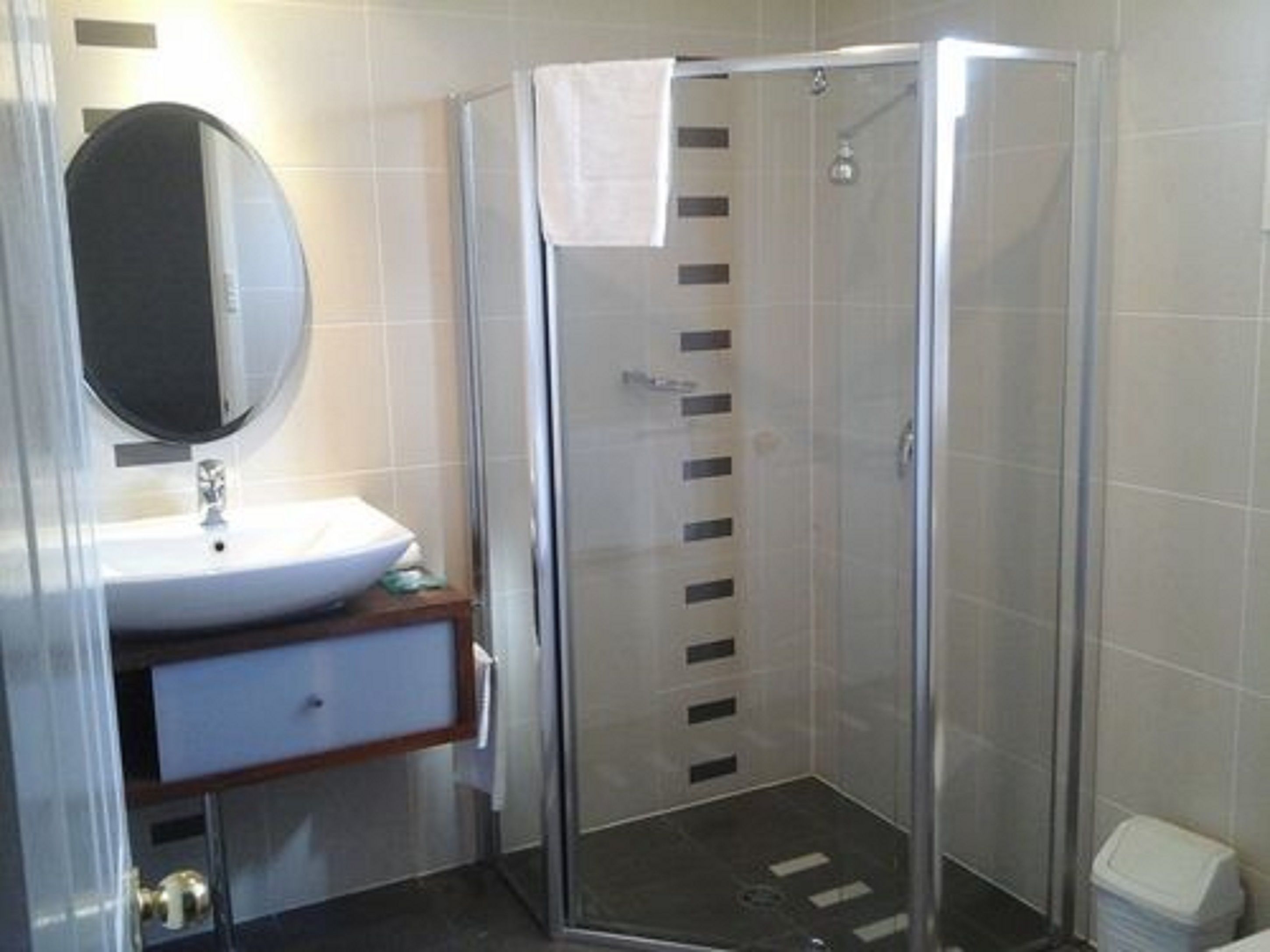A modern bathroom with a glass-enclosed shower, a white sink, and a mirror.