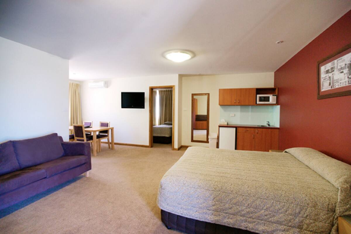 Una habitación de hotel con cama, sofá, escritorio y kitchenette.