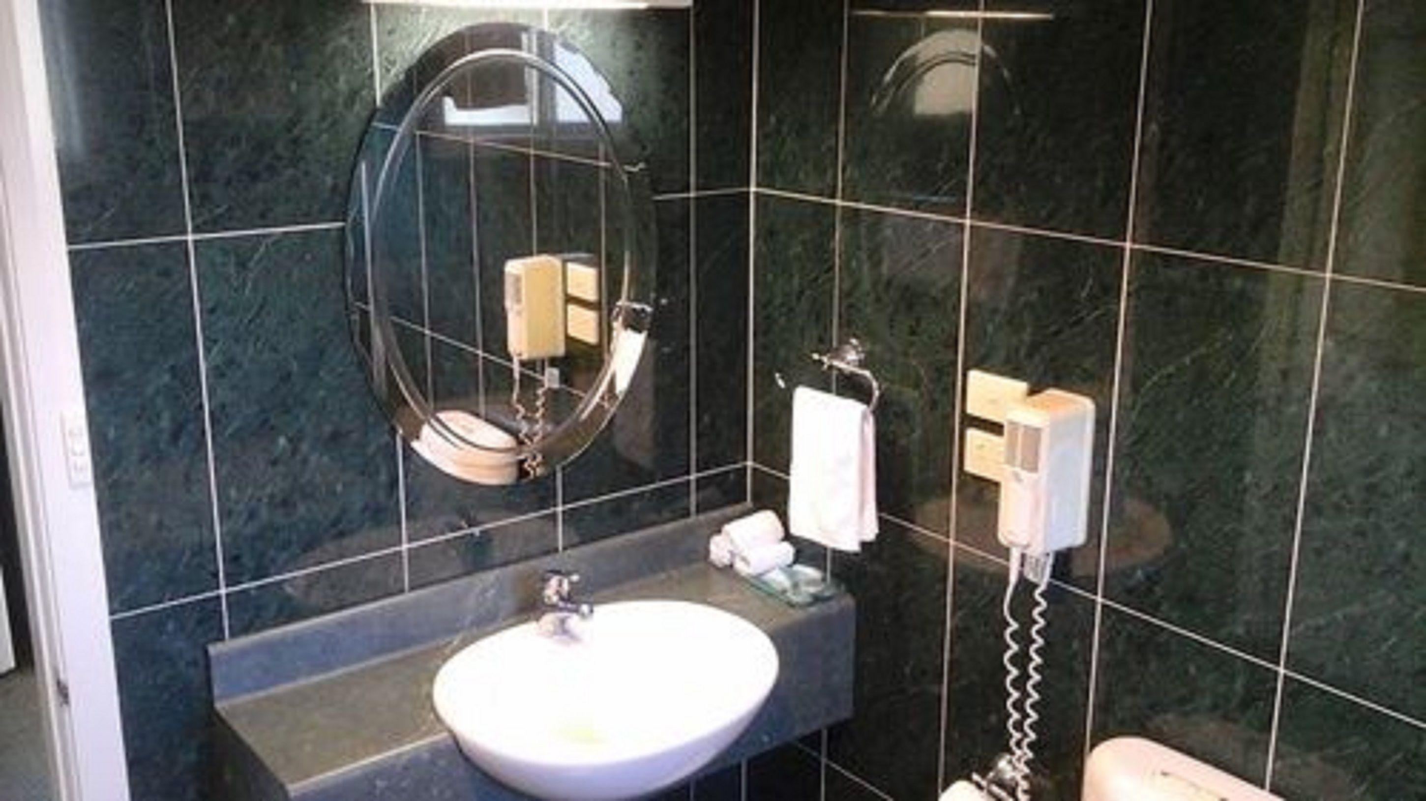 A bathroom with a round sink, a mirror, a towel rack, and a toilet.