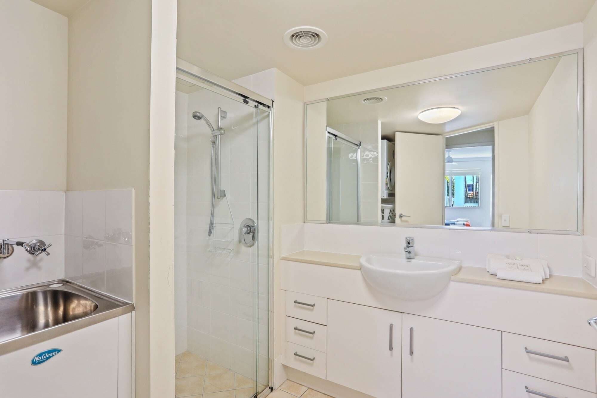 A modern bathroom with a glass-enclosed shower, a sink, and a mirror.