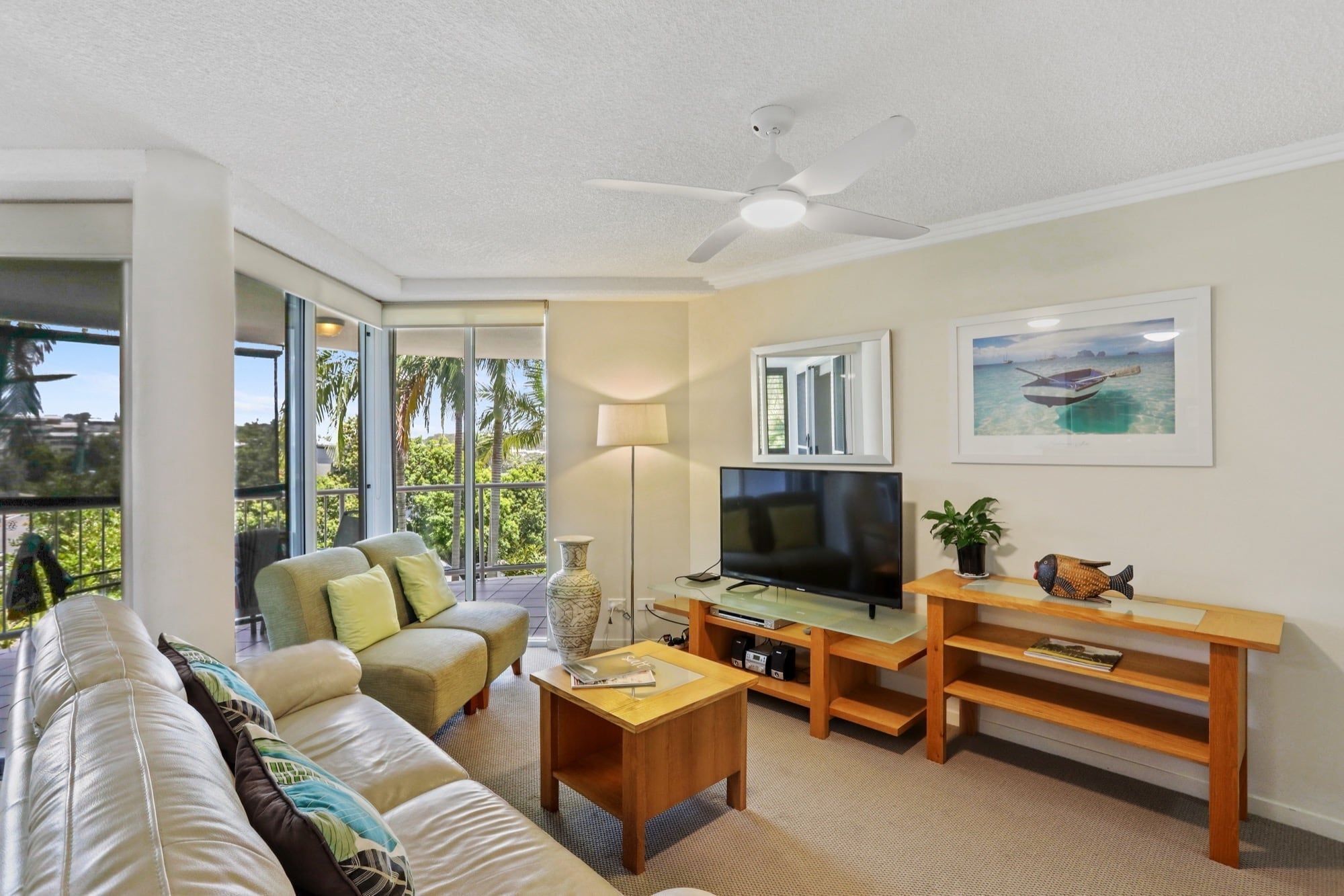 A living room with a sofa, TV, and a ceiling fan.