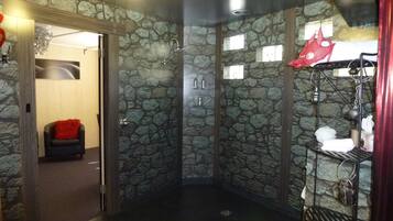 Bathroom features a shower area with a glass door and a black shelf for towels.