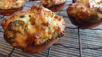 Un muffin con corteza dorada, posiblemente con vegetales y queso, sobre una rejilla enfriadora.