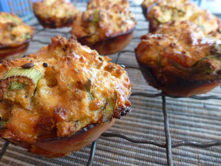 Un muffin con corteza dorada, posiblemente con vegetales y queso, sobre una rejilla enfriadora.