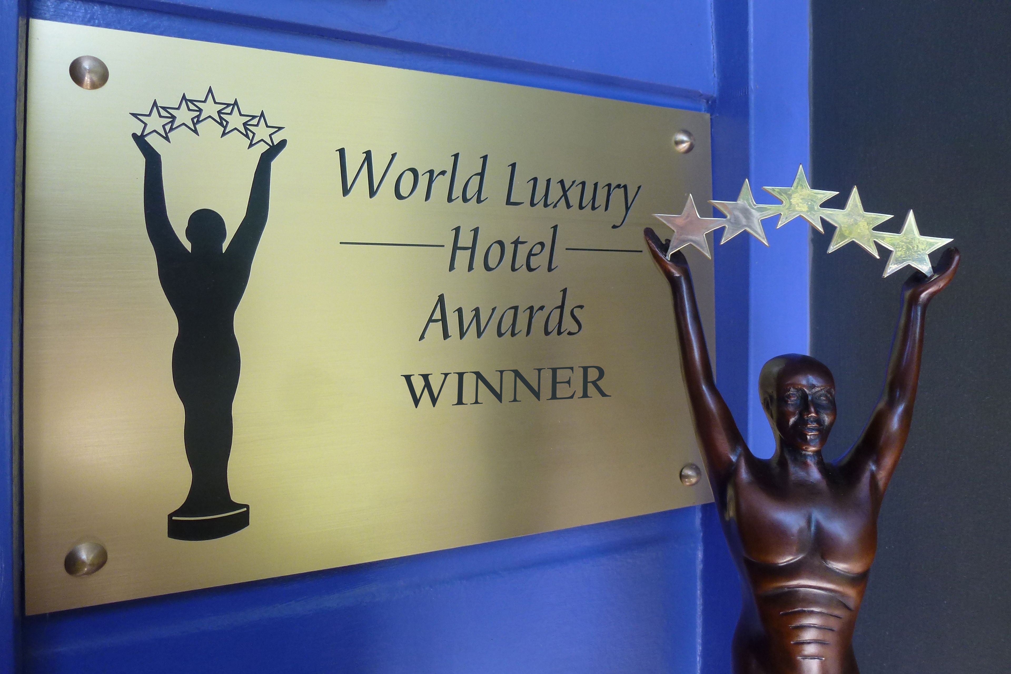 A plaque with the text "World Luxury Hotel Awards Winner" and a silhouette of a person holding stars.