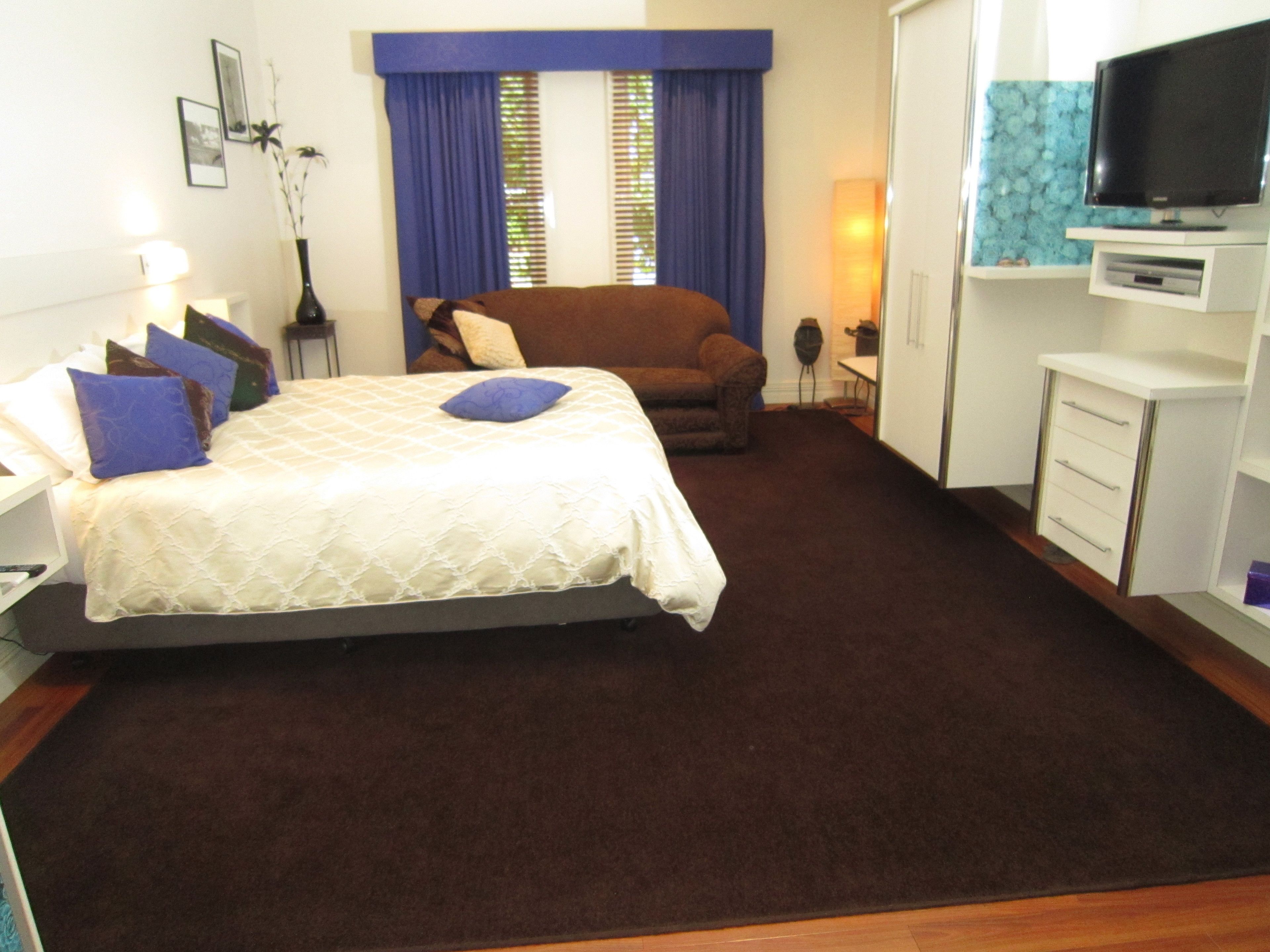 Una habitación de hotel con cama, sofá, televisión y escritorio.