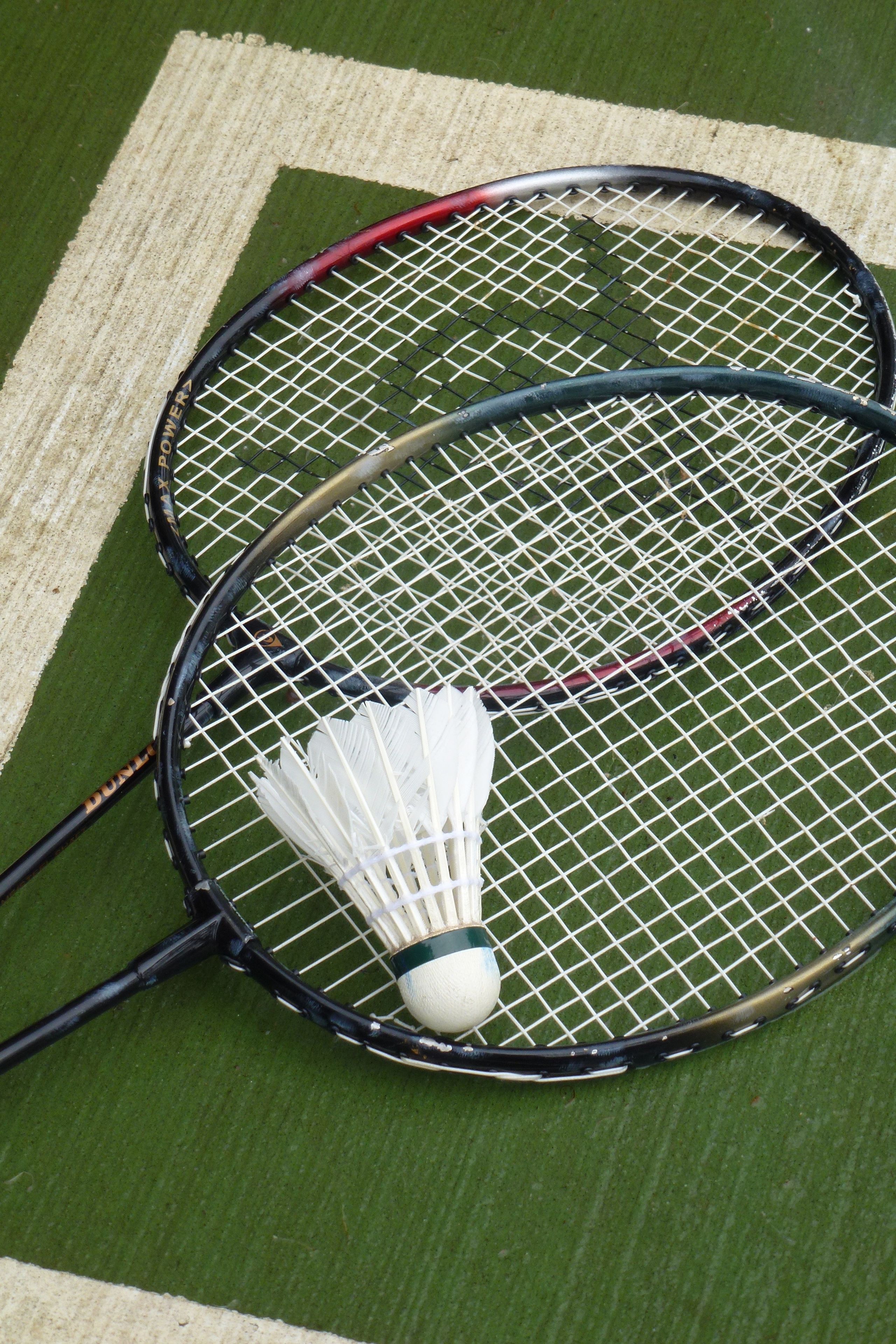 Dos raquetas de bádminton sobre una superficie verde con un volante blanco.