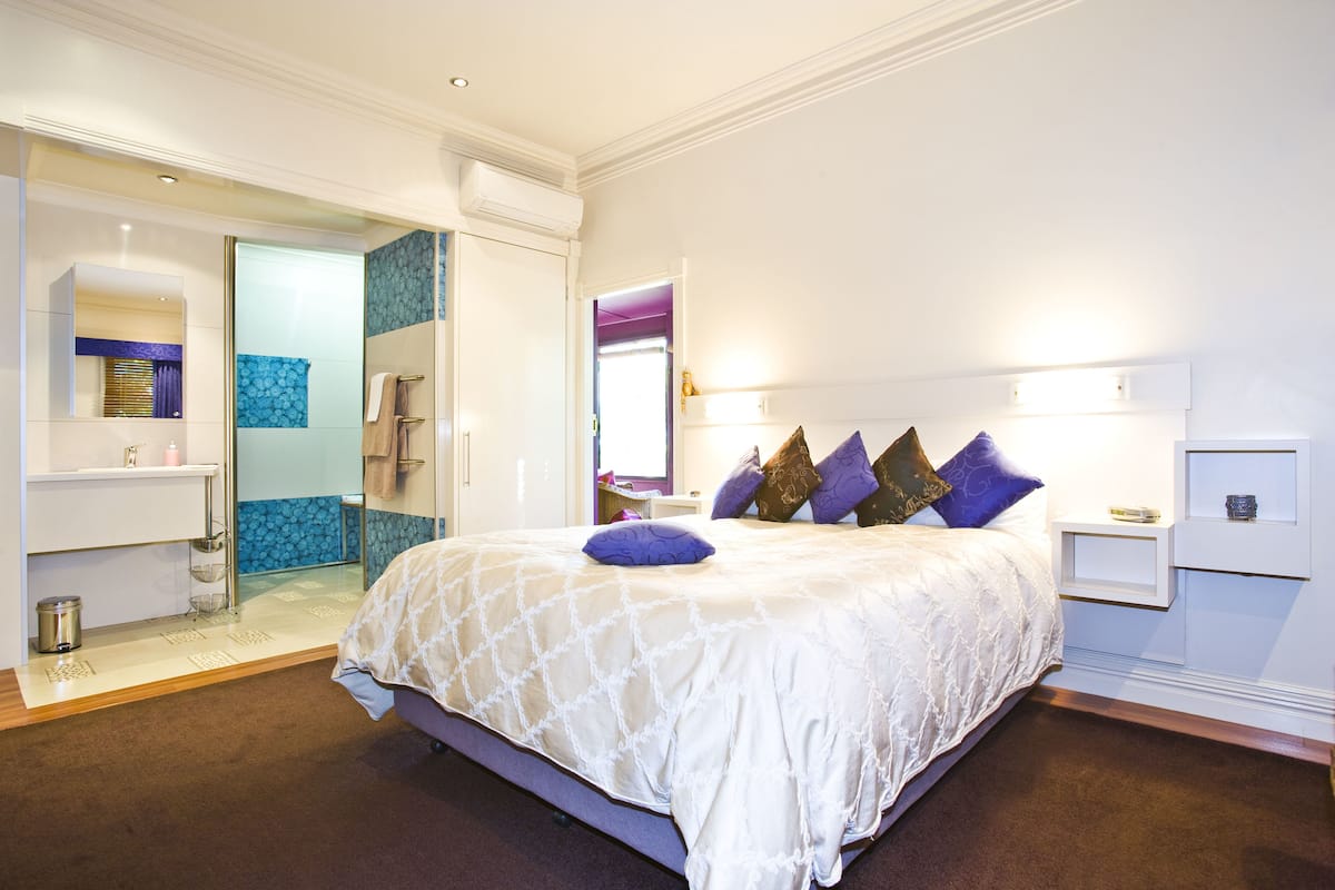 Une chambre moderne dotée d’un grand lit, d’un dressing et d’une salle de bain avec une douche en verre.