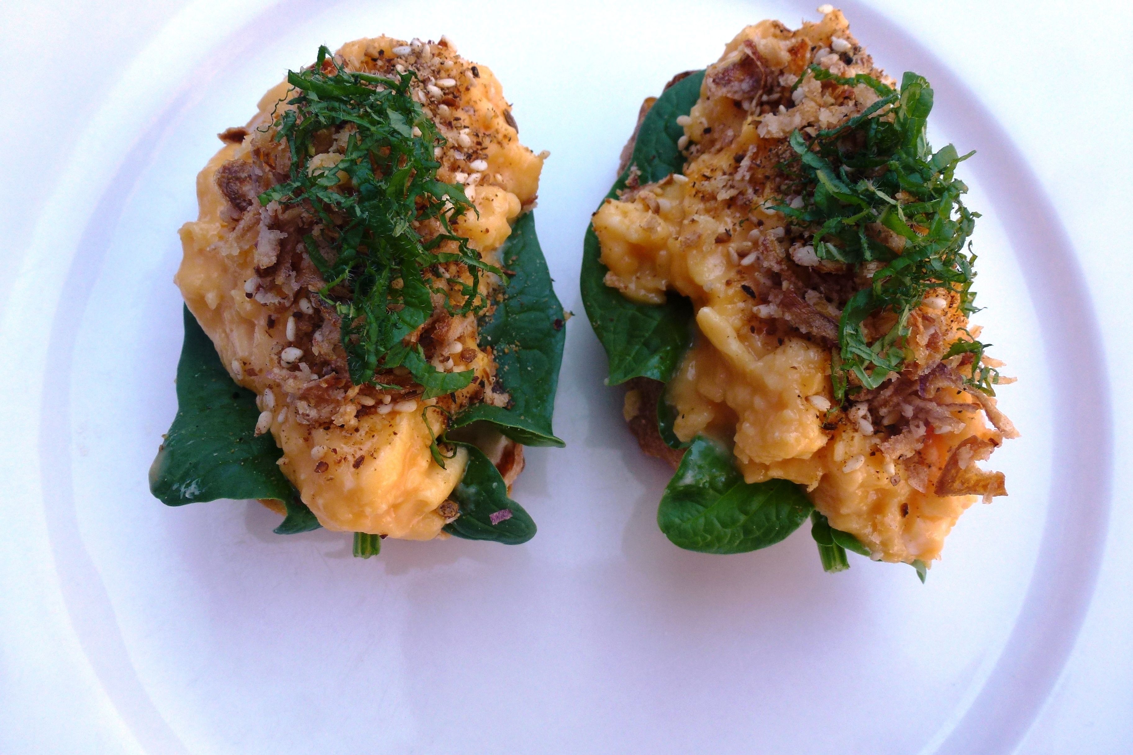 Two stuffed spinach leaves with a creamy filling and crispy topping, served on a white plate.