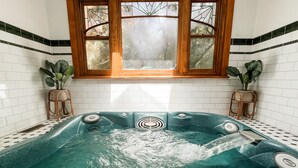 A spa room with a large bathtub, wooden window frames, and white tiled walls. - Woolrich Historic Garden Cottage (Olinda)