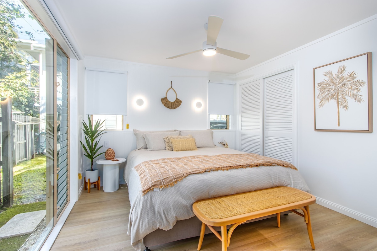 A bedroom with a bed, bedside table, and a bench.