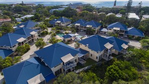 A residential area with multiple houses featuring blue roofs and a swimming pool. - Hastings Cove Waterfront Holiday Apartments (Hastings Point)