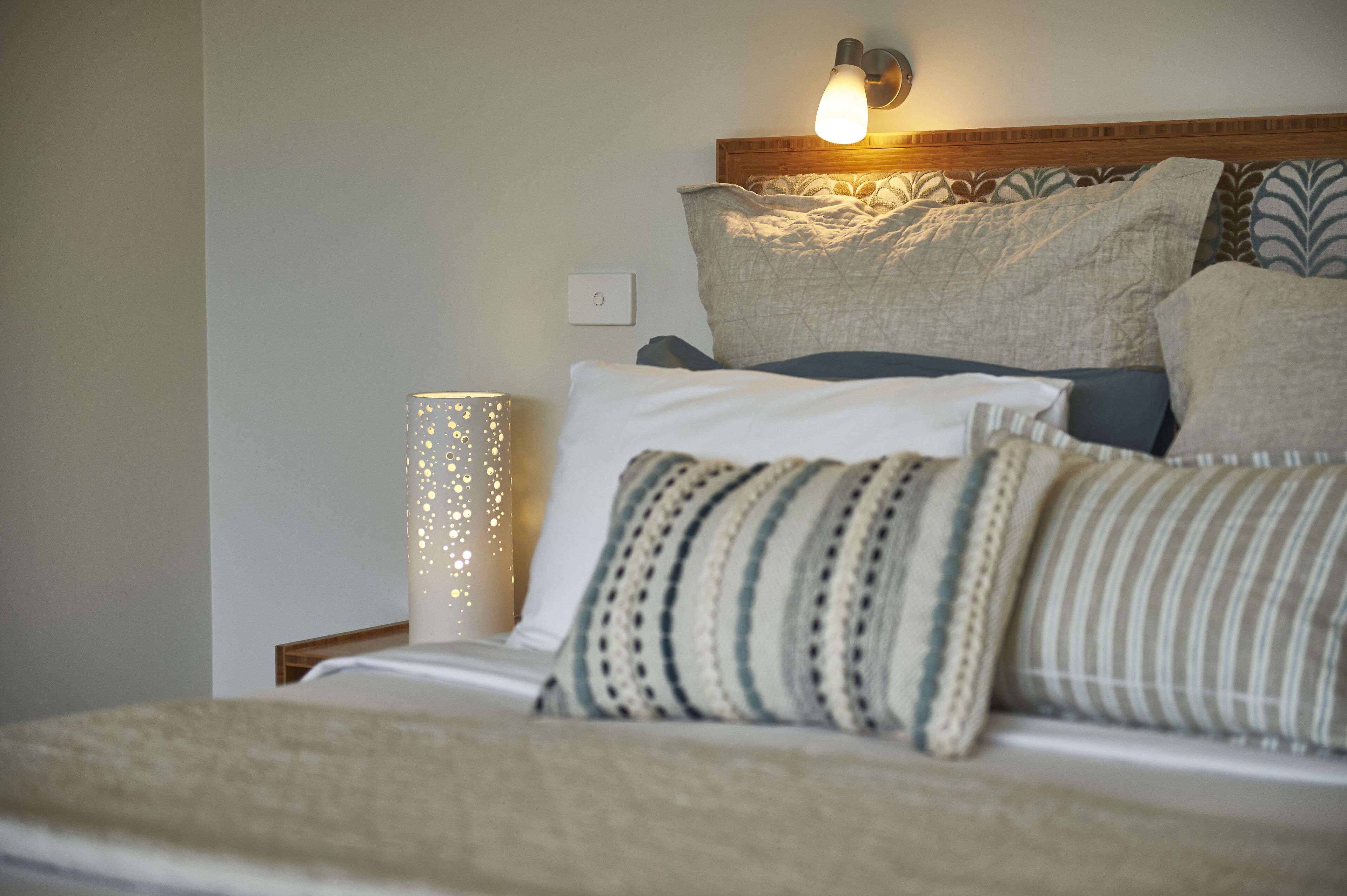 A neatly made bed with multiple pillows and a bedside lamp.