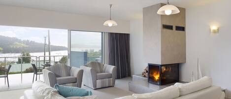 A modern living room with a fireplace, a sofa, and a view of the outdoors.
