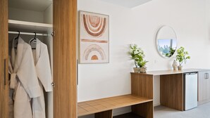 Une salle de bain moderne avec un banc en bois, un miroir et une œuvre d’art accrochée au mur.