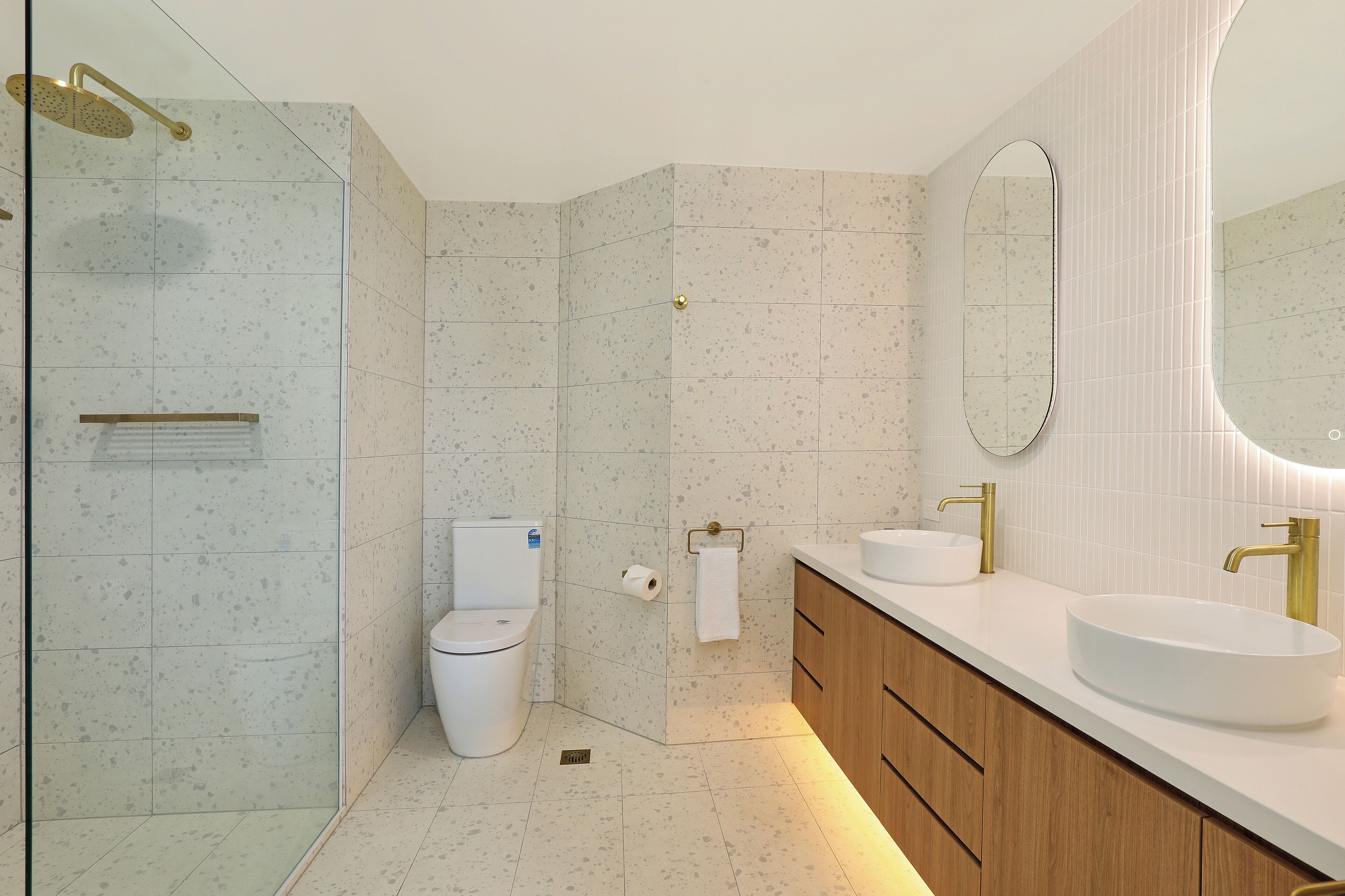 A modern bathroom with a shower, toilet, and vanity with a sink and mirror.