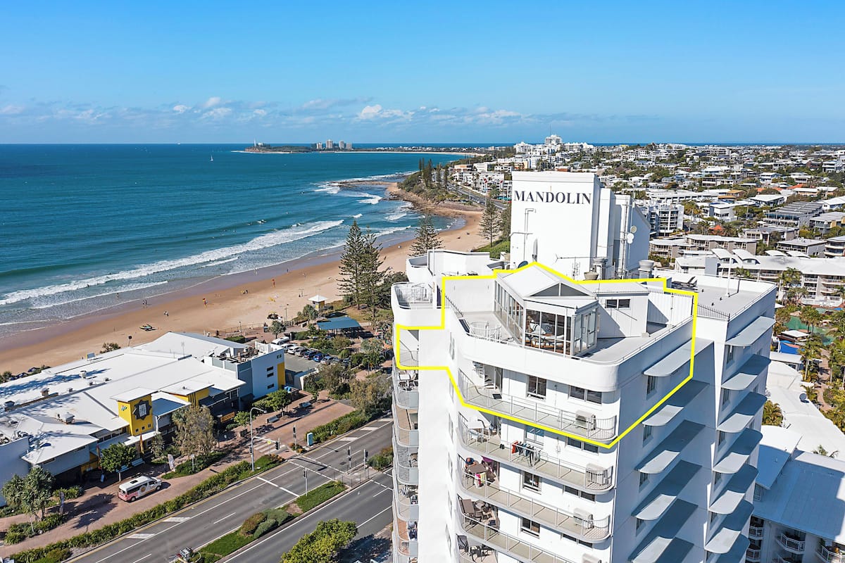 A high-rise hotel with a rooftop terrace, located near a beach and ocean.