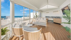 Un grand balcon aménagé avec des meubles en osier, un coin repas et une cuisine.