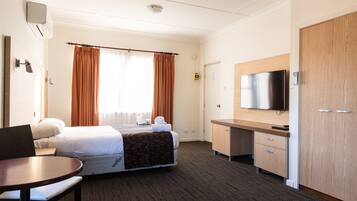 A hotel room with a bed, a desk, a television, and a wardrobe.