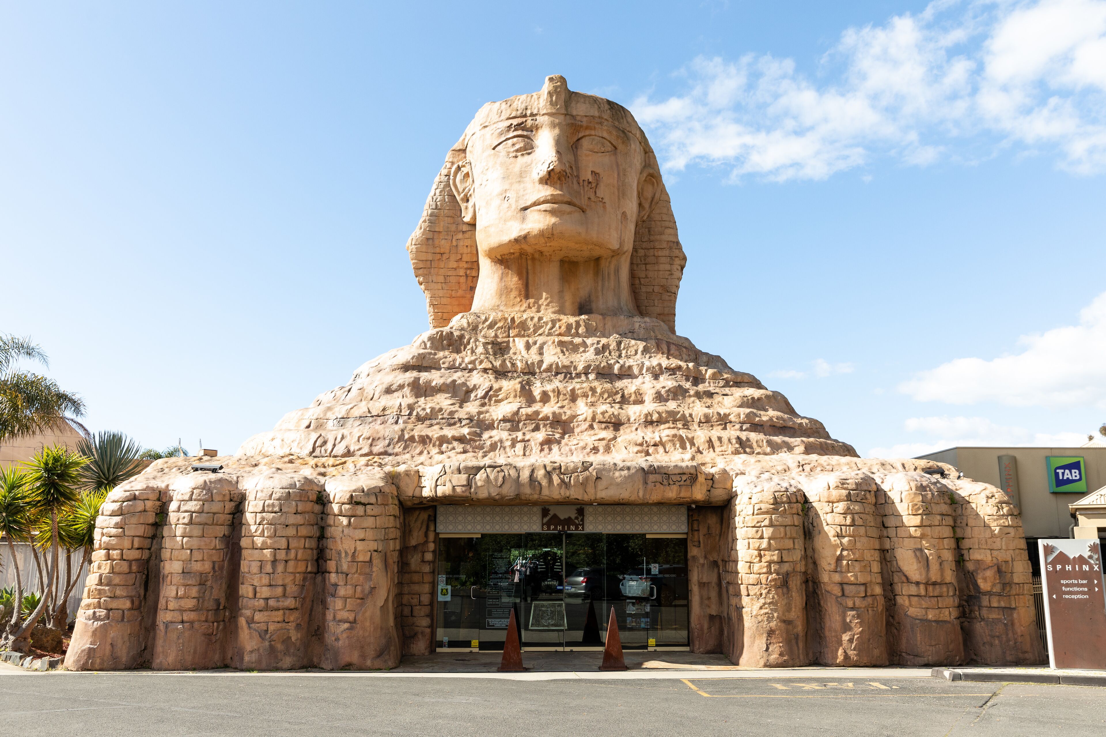 A large, ancient-looking structure resembling a pyramid with a large head sculpture at the top, possibly a tourist attraction.
