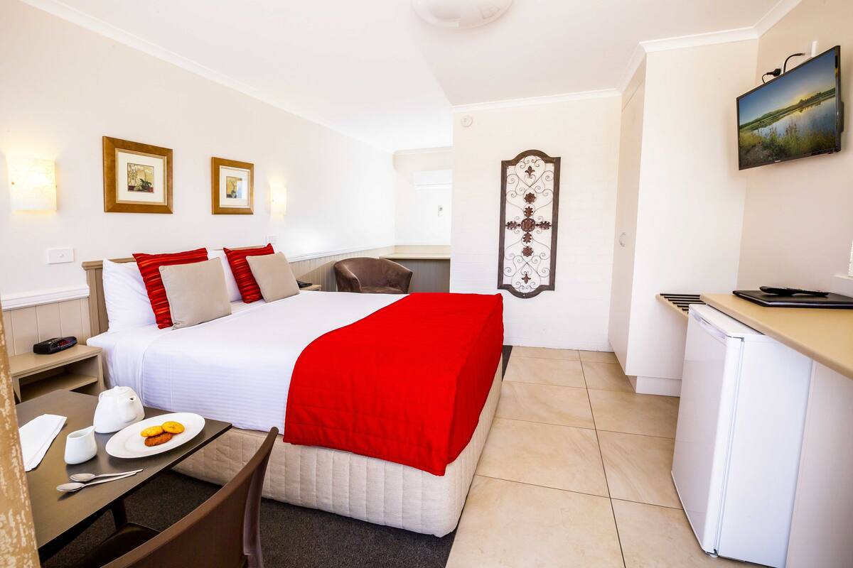 Une chambre d’hôtel avec un lit, une table de chevet et une petite kitchenette.