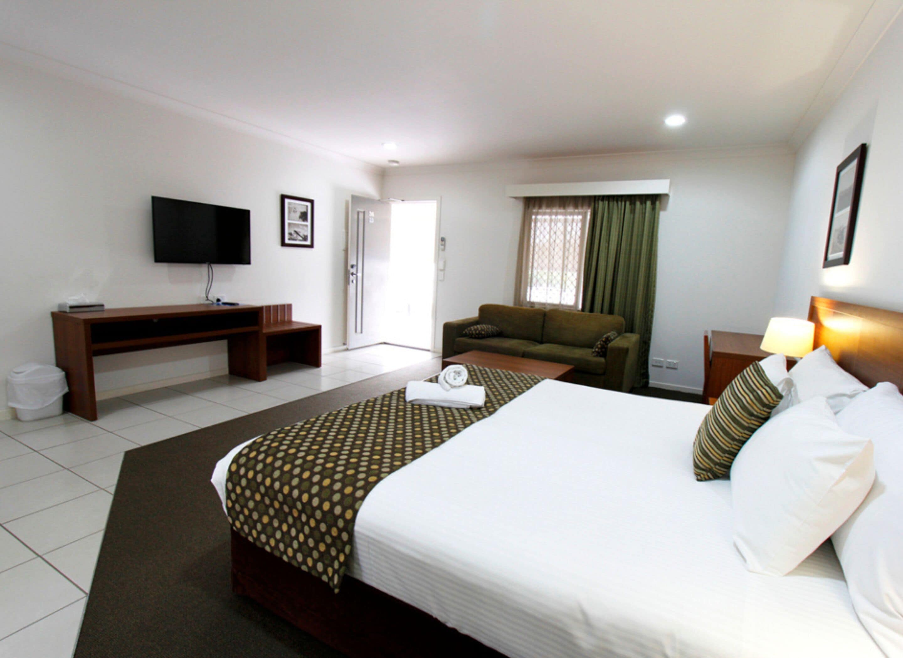 A hotel room with a bed, a sofa, a TV, and a desk.