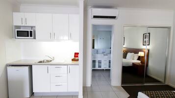 A compact hotel room with a kitchenette, a bathroom, and a bedroom.