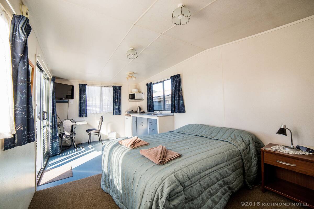 Une chambre comprenant un lit, un bureau, une chaise et une petite kitchenette.