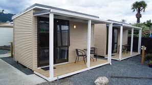 A modern, single-story mobile home with a covered patio area, two chairs, and a small table. - Richmond Motel & Holiday Park (Richmond)