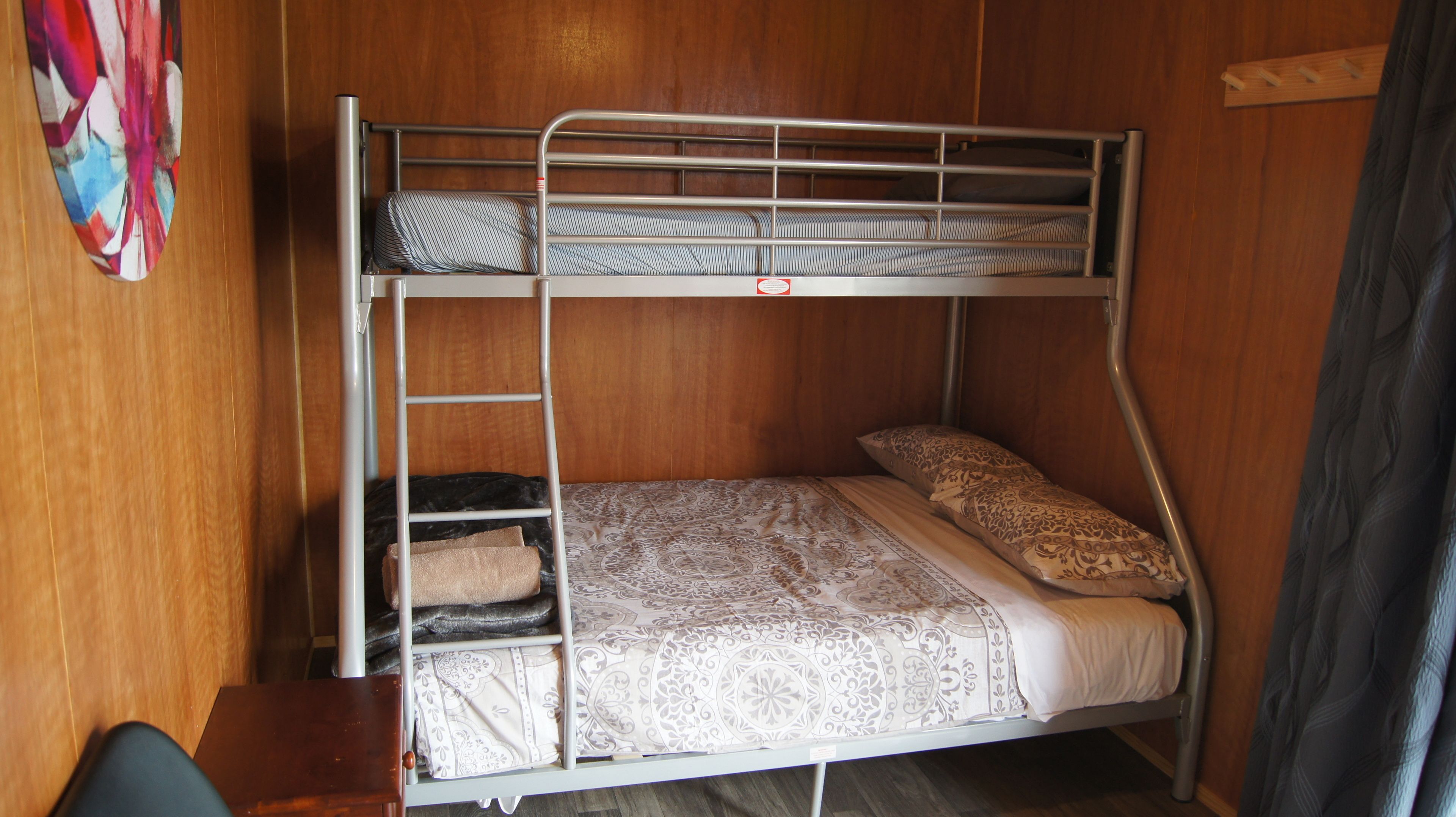 Una cama litera con escalera, una colcha estampada y un cojín con diseño paisley.