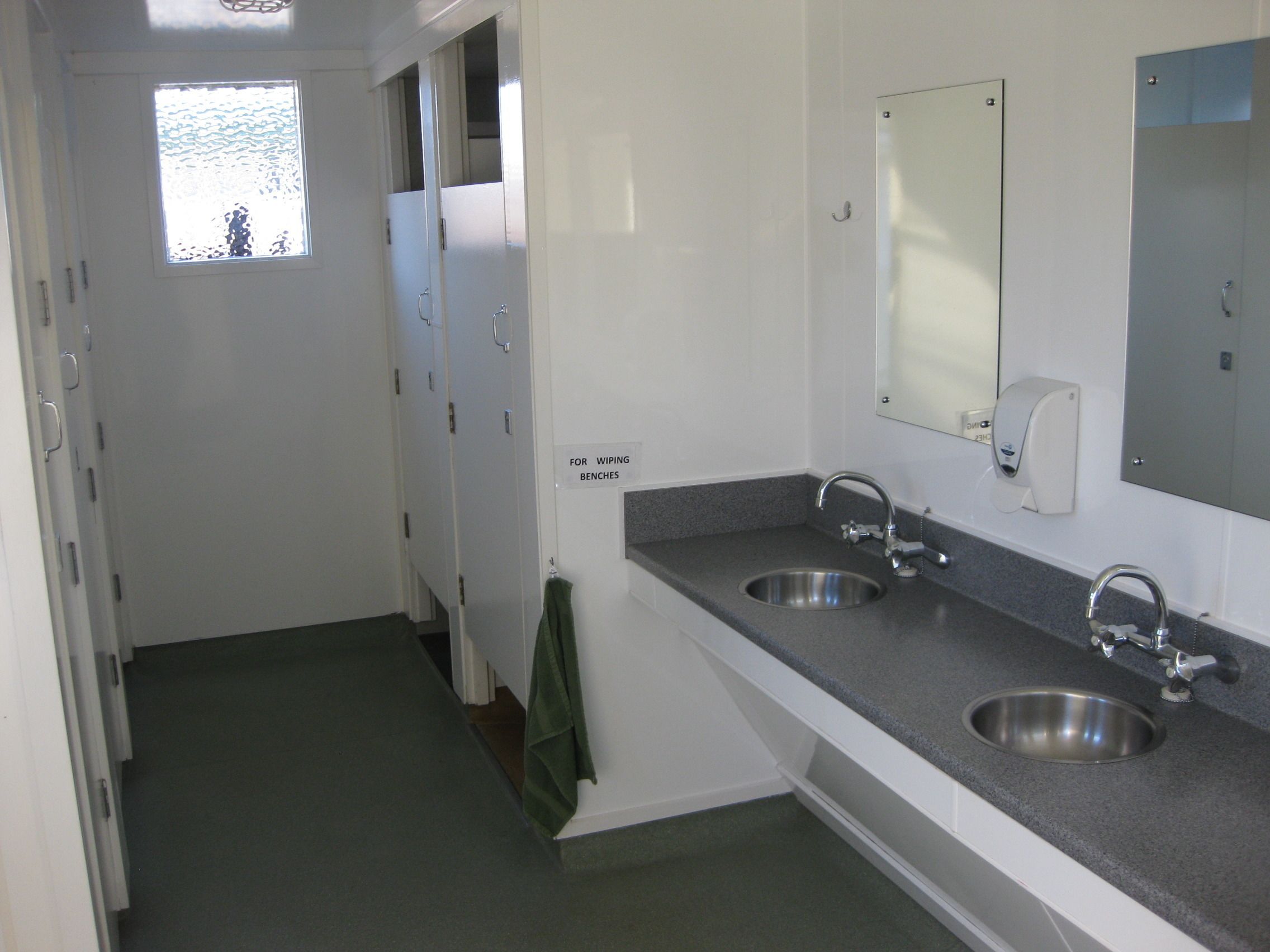 A bathroom with two sinks, a mirror, and a towel rack.