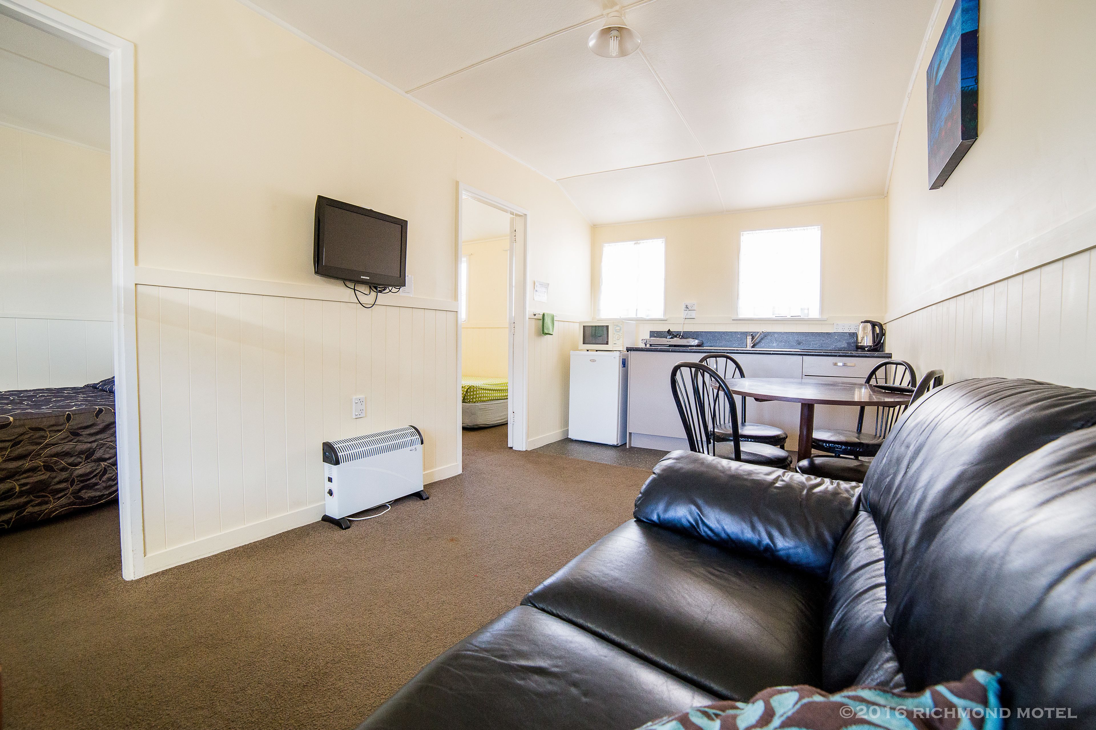 A compact living space with a kitchenette, a dining area, and a seating area with a leather couch.