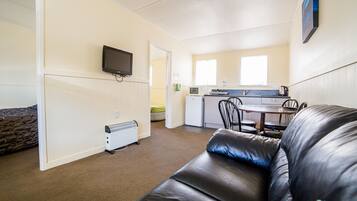 A compact living space with a kitchenette, a dining area, and a seating area with a leather couch.