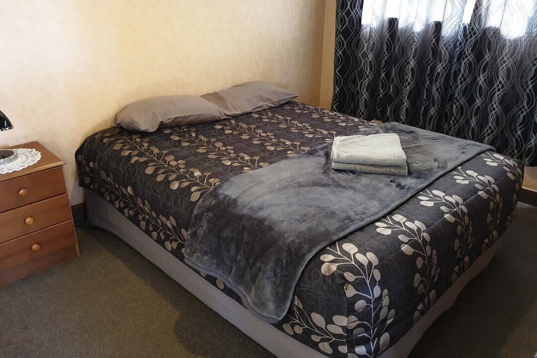 A neatly made bed with a floral-patterned bedspread and two pillows.